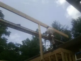 Carpenter setting a ridge beam over a new addition frame — Ice Dam Removal by Roofing Brothers in Glenmont