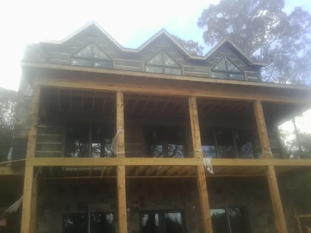 Dormers and porch framing on a large log home under construction — Roof Coating work by our crew in Glenmont