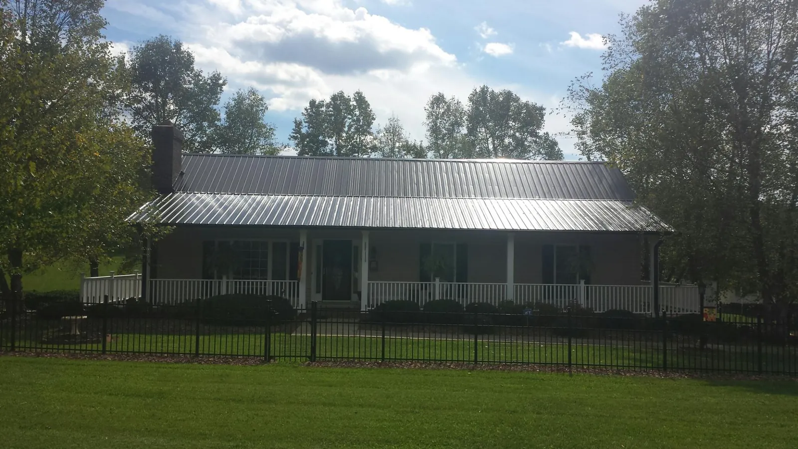 Gray metal roof on a brick ranch with a full width front porch — Gutter Guard Installation work by our crew in Glenmont