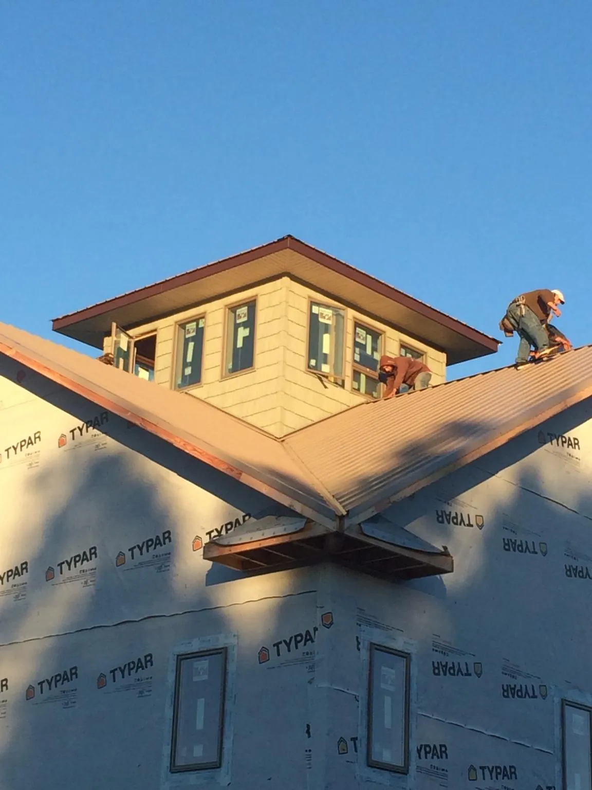 Roofers working around a rooftop cupola on a new metal roof at sunset — Roof Waterproofing in Glenmont by Roofing Brothers